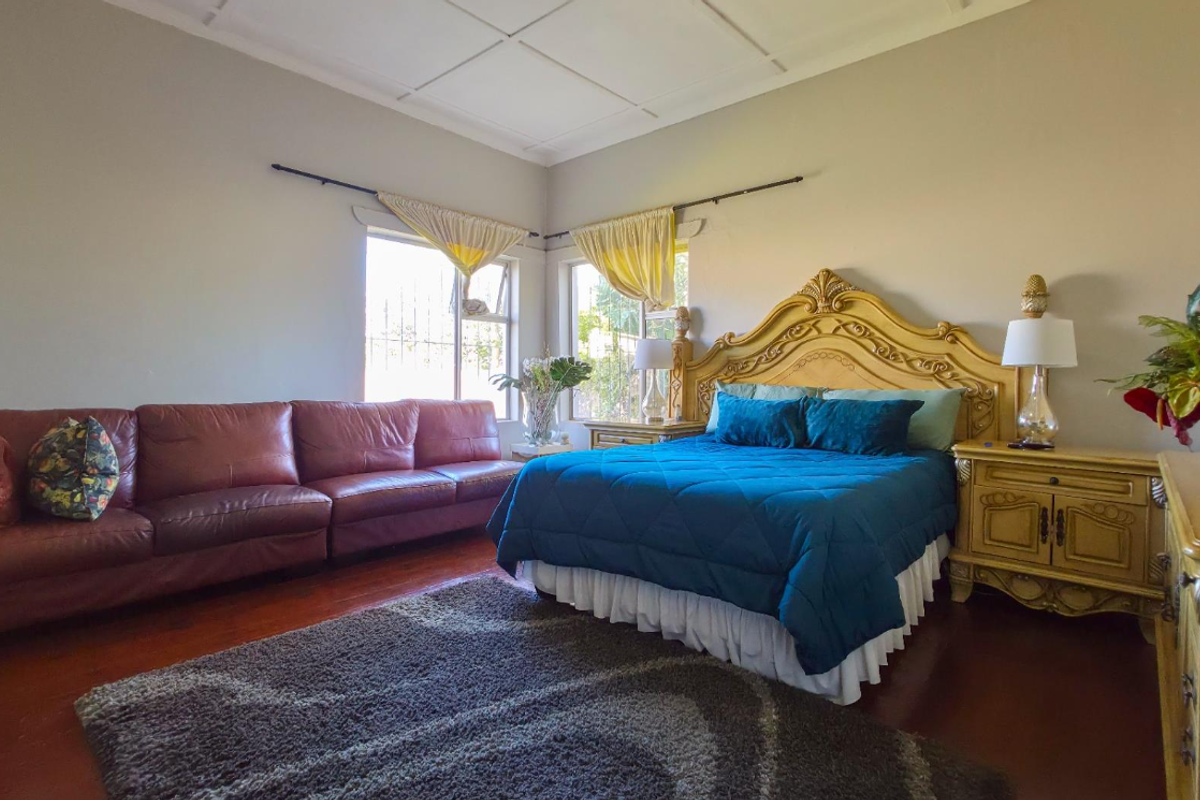 Spacious bedroom featuring polished hardwood flooring, a coffered ceiling, and dual aspect windows providing natural light.