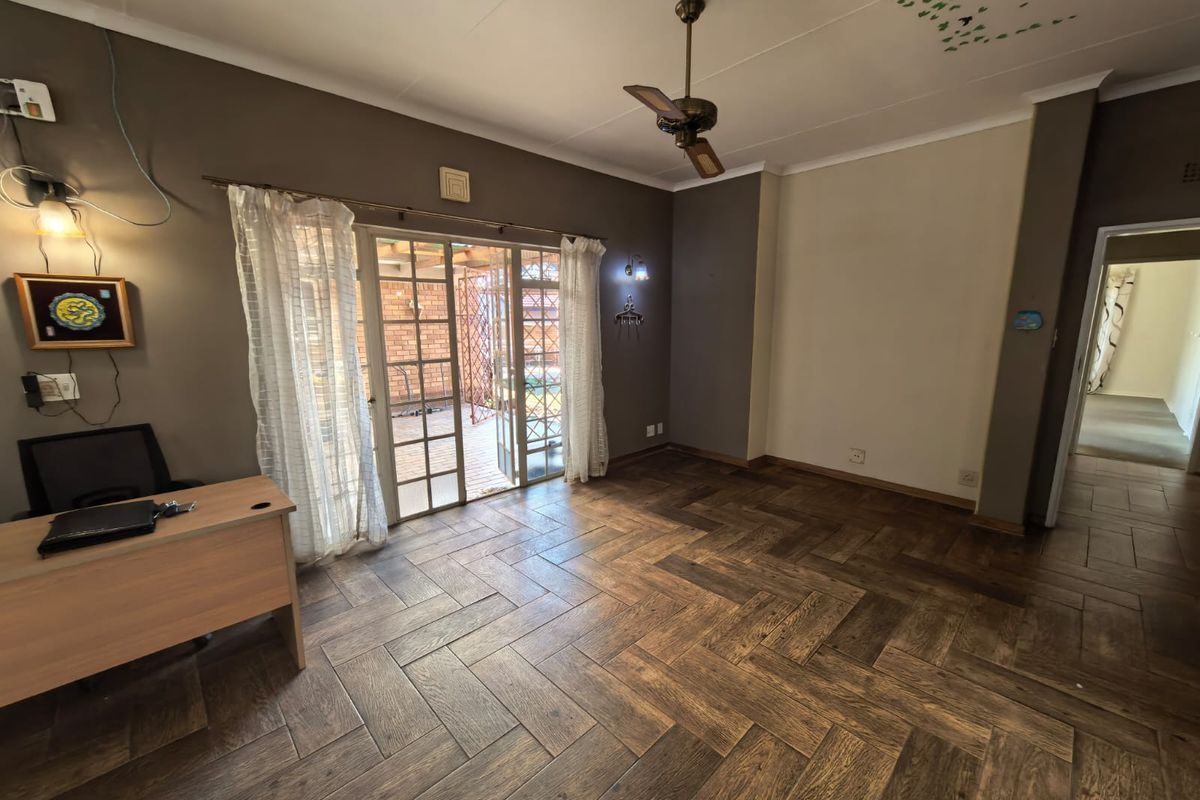 Living room featuring herringbone wood flooring, a ceiling fan, and sliding glass doors providing access to the outdoor patio area.