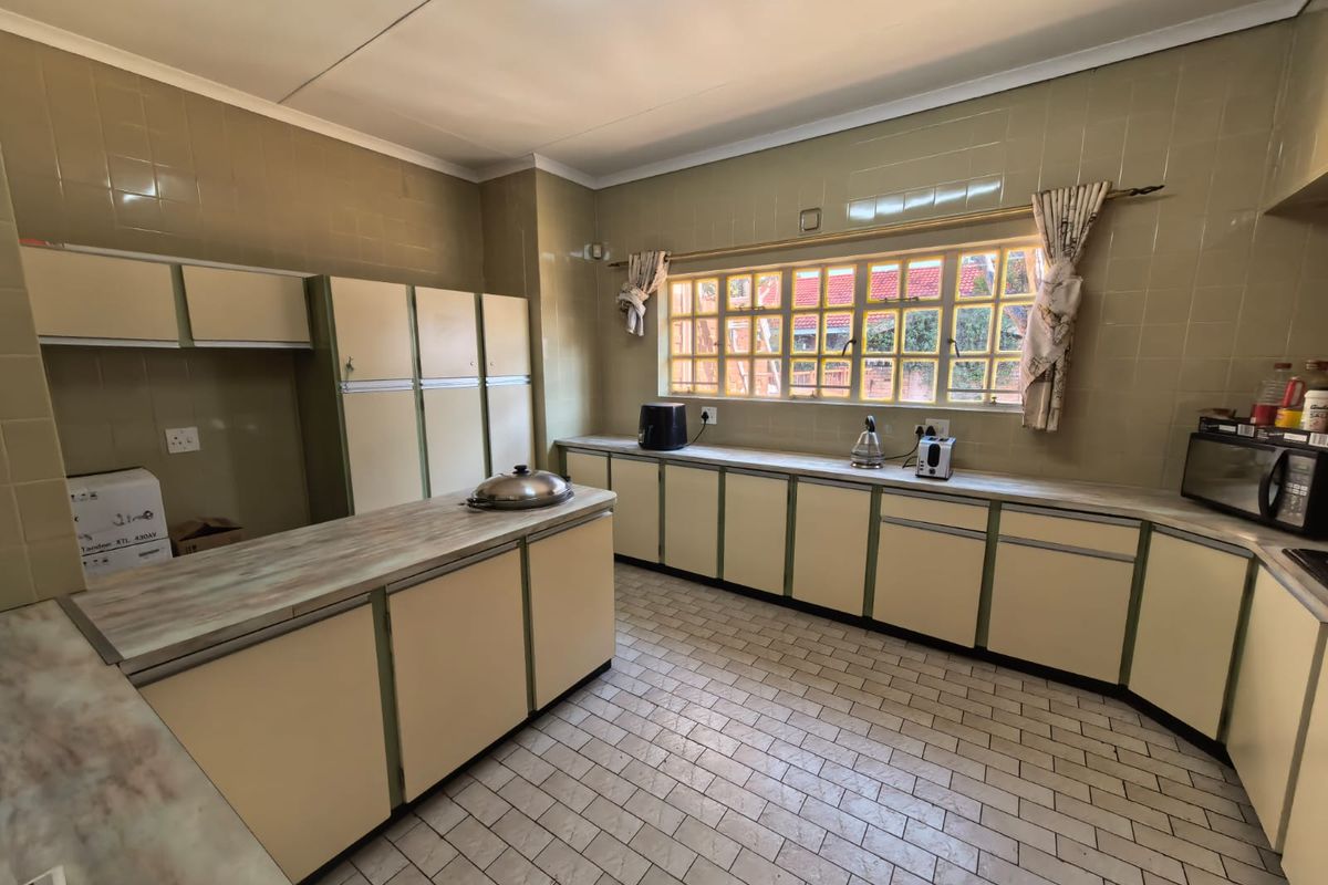 A spacious, dated kitchen featuring extensive built-in cabinetry, tiled walls, and tiled flooring, offering significant potential for a modern renovation.