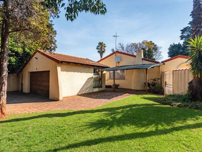 Front view of a single-story house featuring a paved driveway, attached garage, and a well-maintained front lawn.