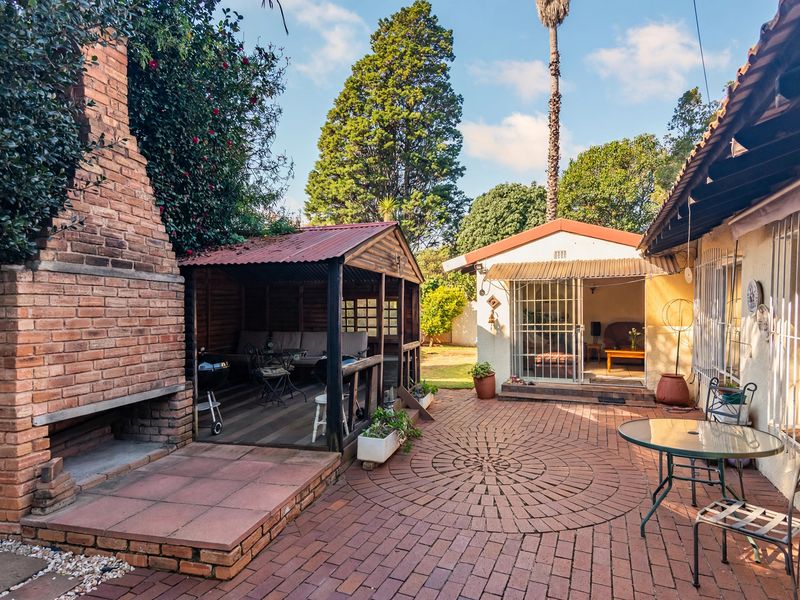 Outdoor patio area featuring a built-in brick fireplace, a timber gazebo, and brick paving, providing a functional space for outdoor entertaining.