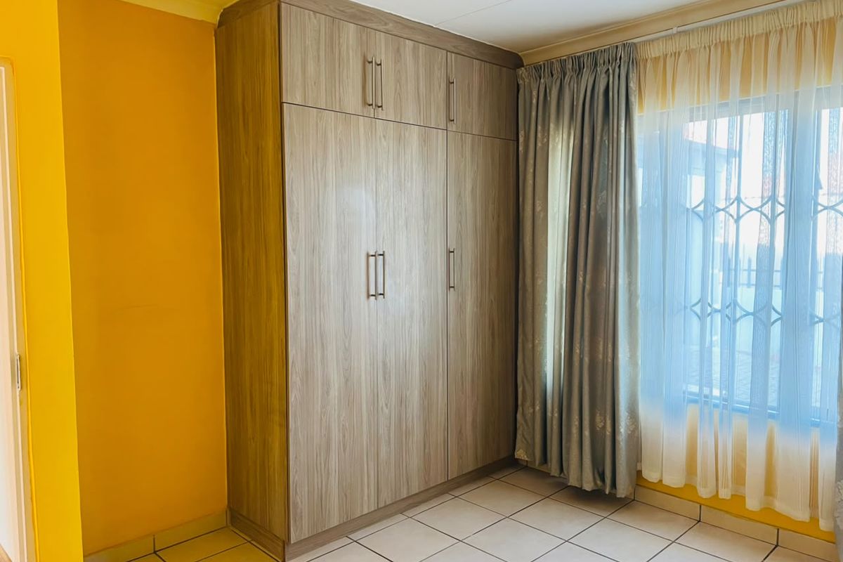 A bright bedroom featuring tiled flooring and a large, modern built-in wardrobe with ample storage space.