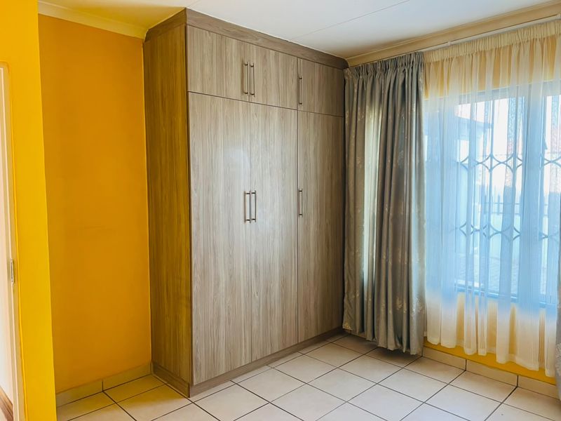 A bright bedroom featuring tiled flooring and a large, modern built-in wardrobe with ample storage space.