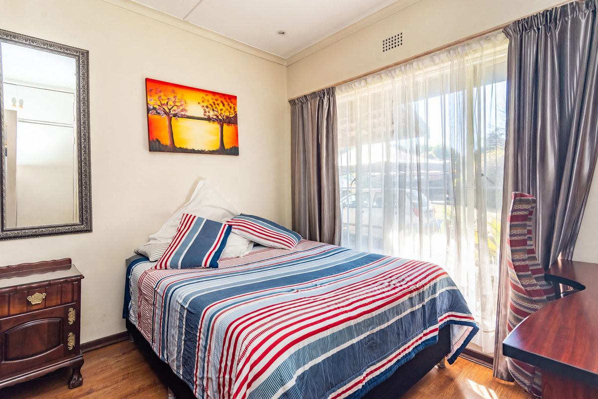 A bedroom featuring laminate flooring and a sliding glass door providing natural light and access to the exterior.