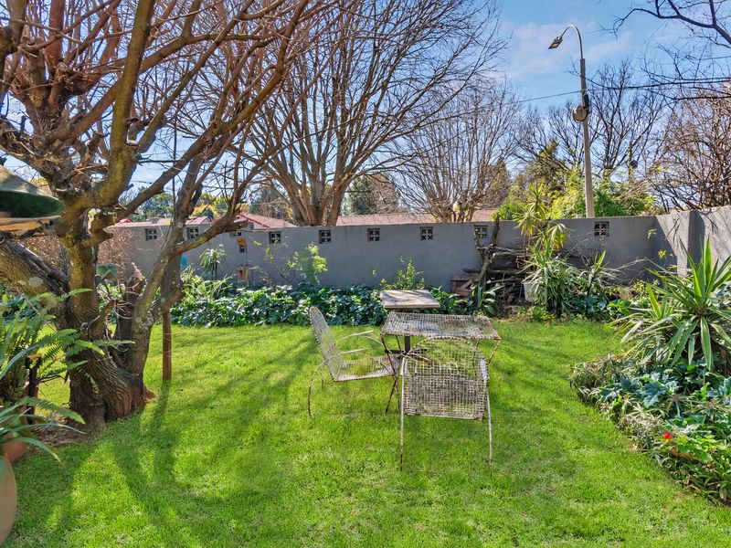 A private garden area featuring a well-maintained lawn, established trees, and a perimeter boundary wall with decorative ventilation blocks.