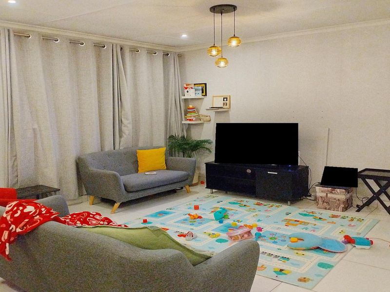 A comfortable living room featuring tiled flooring and recessed lighting, providing a functional space for relaxation and family activities.