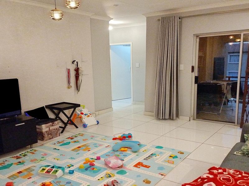 Spacious living room featuring neutral tiled flooring, coving, and a large sliding glass door providing access to the outdoor area.