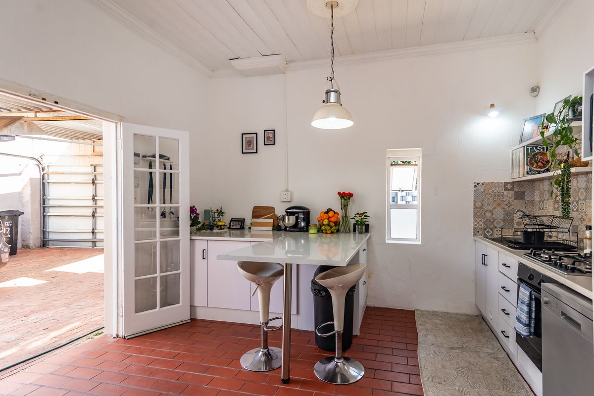 Functional kitchen featuring built-in cabinetry, gas hob, oven, and a breakfast bar, with direct access to an outdoor area through a glass-paneled door.