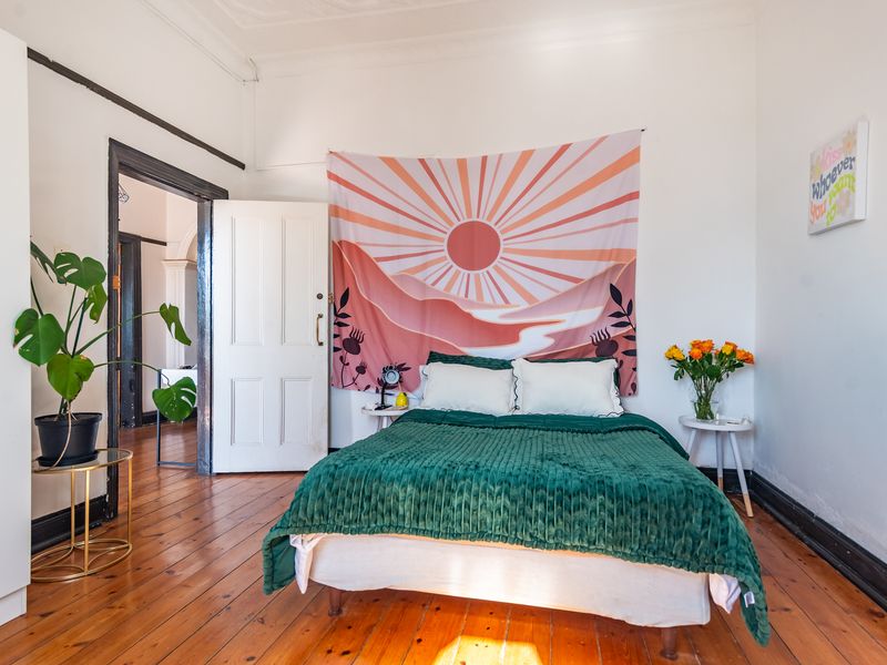 A bedroom featuring original timber flooring, classic panelled doors, and traditional skirting boards, offering a character-filled space with potential for modern updates.