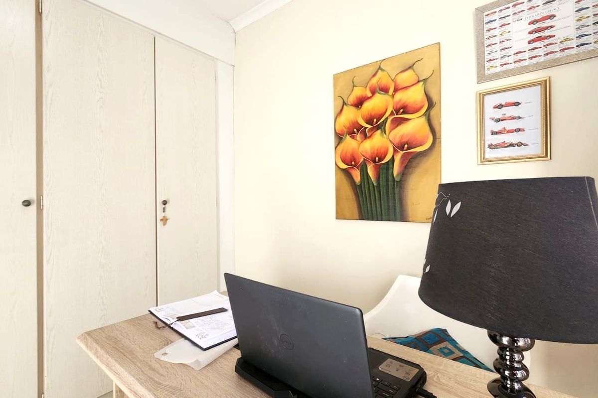 A functional bedroom space featuring a built-in wardrobe and neutral wall finishes, suitable for use as a bedroom or home office.