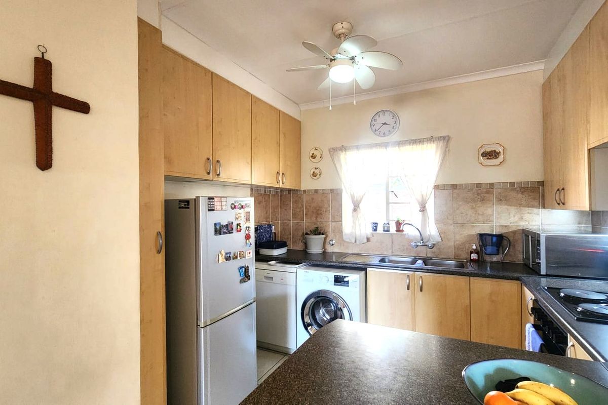 A functional kitchen featuring light wood-finish cabinetry, granite countertops, a tiled backsplash, and integrated space for laundry appliances.