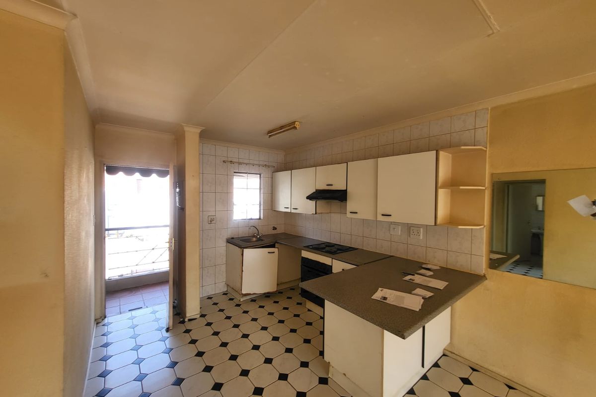 A dated kitchen featuring built-in cabinetry, a hob, oven, and extractor fan, with direct access to an outdoor balcony area.