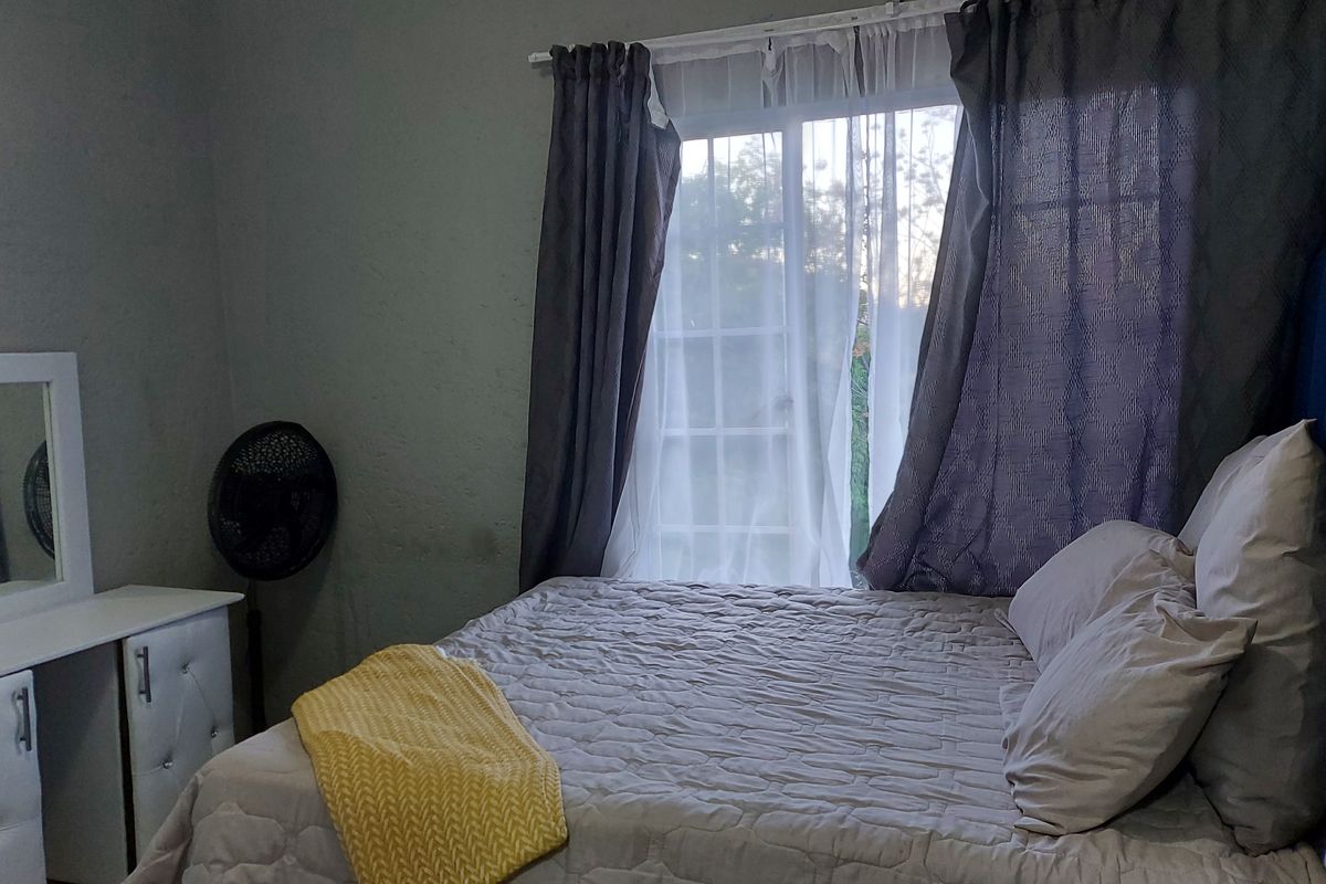 A functional bedroom featuring a window with natural light and standard finishes, suitable for comfortable living.