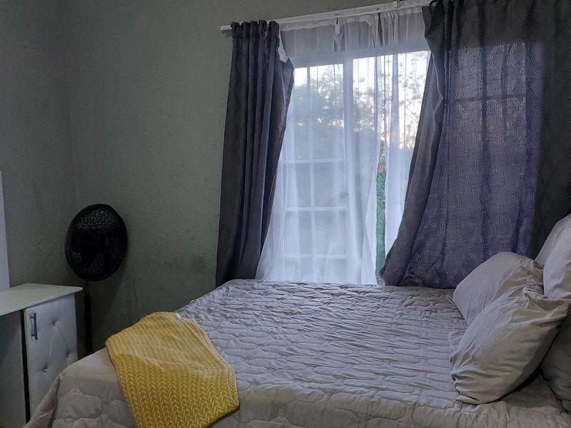 A functional bedroom featuring a window with natural light and standard finishes, suitable for comfortable living.