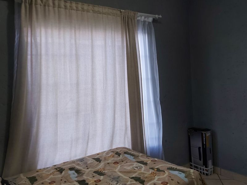 A bedroom featuring tiled flooring and a window with installed curtain rods.