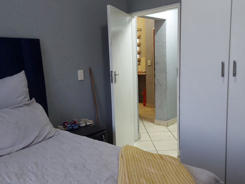 Bedroom featuring built-in wardrobe storage, tiled flooring, and direct access to an adjoining room.