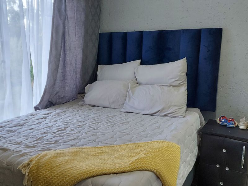 A bedroom featuring textured walls and a large window with sheer curtains, providing a neutral base for interior design updates.