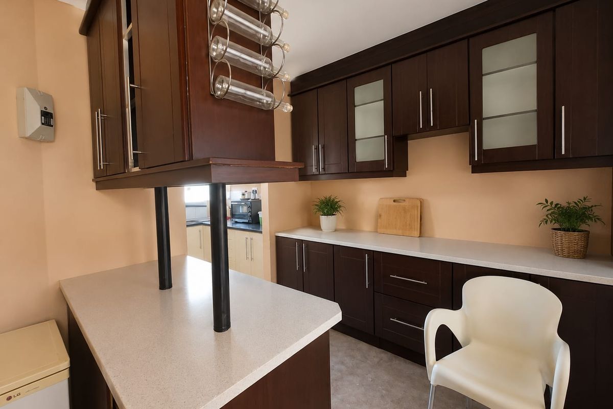 A functional kitchen featuring dark wood cabinetry, light-toned laminate countertops, and a breakfast bar with integrated wine storage.
