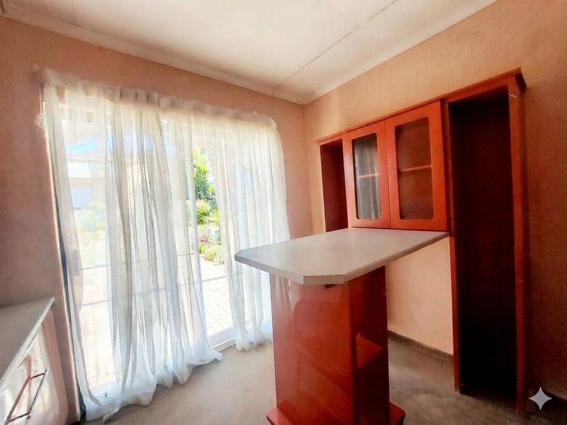 A kitchen area featuring built-in cabinetry, a breakfast bar, and a sliding glass door providing access to the garden.