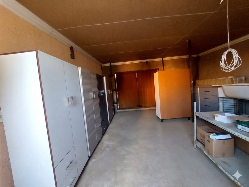 A functional garage space featuring built-in storage cabinetry, a utility sink, and concrete flooring, offering potential for workshop or storage use.