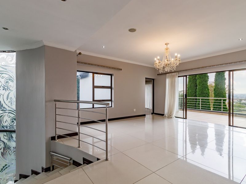 Spacious open-plan living area featuring polished porcelain tiles, a modern stainless steel balustrade, and sliding doors leading to a balcony with scenic views.