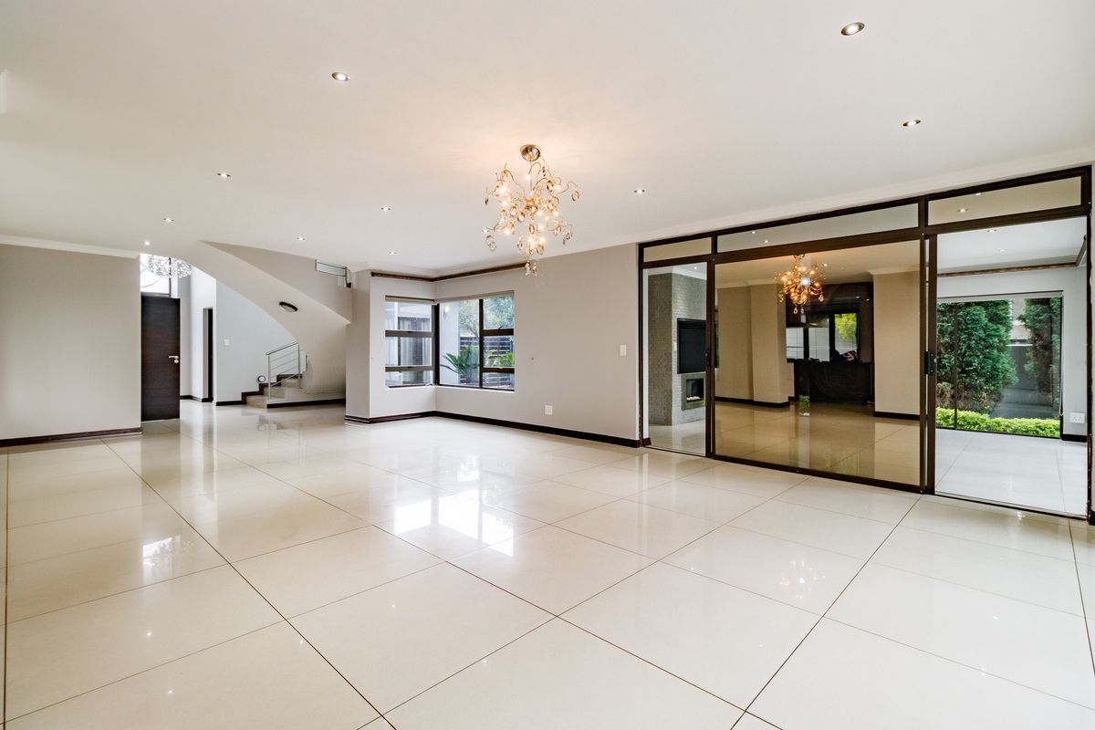 Spacious, open-plan living area featuring polished porcelain tiles, recessed lighting, and large sliding glass doors leading to an outdoor space.