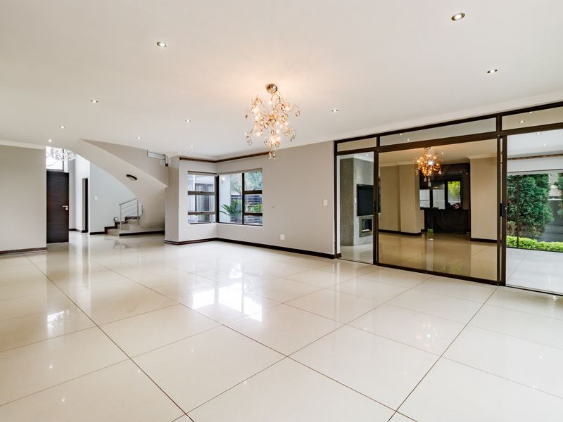Spacious, open-plan living area featuring polished porcelain tiles, recessed lighting, and large sliding glass doors leading to an outdoor space.