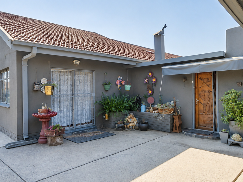 Front exterior view of the house featuring a concrete driveway, tiled roof, garage access, and a covered entrance area with a brick planter.