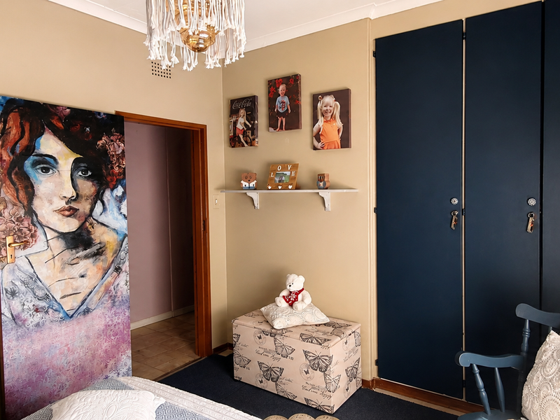 A bedroom featuring dark blue built-in cupboards, neutral wall tones, and carpeted flooring, providing a functional space with storage.
