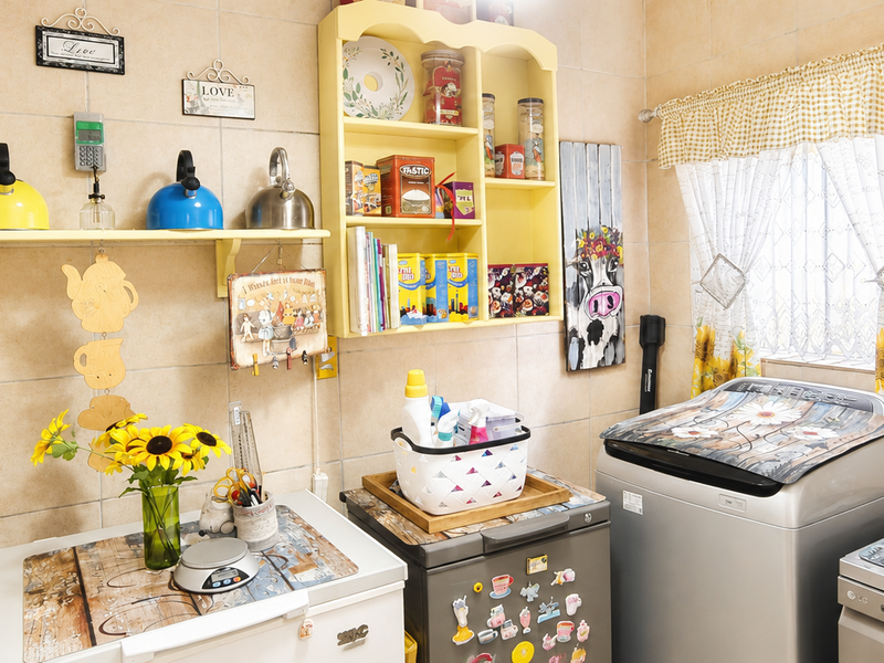 A functional laundry area featuring full-height ceramic wall tiling, wall-mounted storage shelving, and dedicated plumbing connections for appliances.