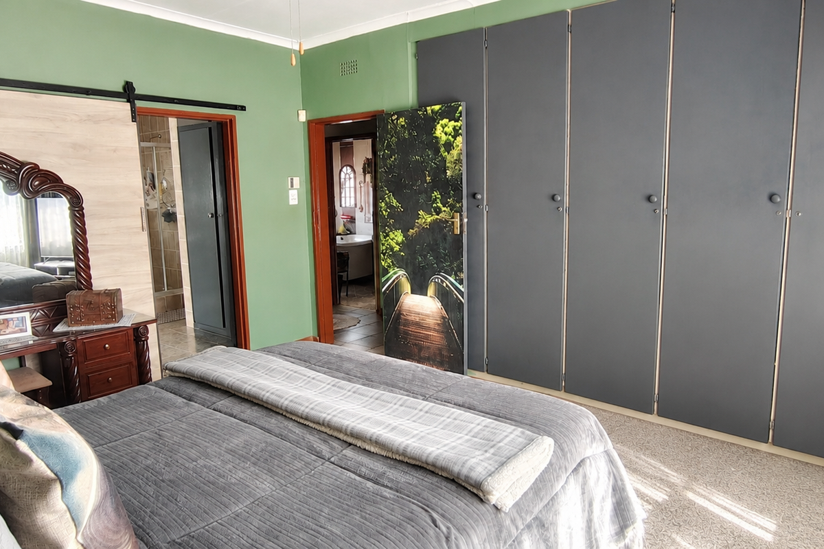 Spacious bedroom featuring extensive built-in cupboards, carpeted flooring, and direct access to an en-suite bathroom.