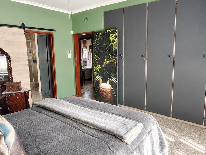 Spacious bedroom featuring extensive built-in cupboards, carpeted flooring, and direct access to an en-suite bathroom.