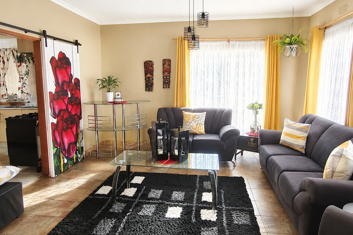 A comfortable living room featuring tiled flooring, a decorative sliding barn door, and direct access to the adjacent kitchen area.