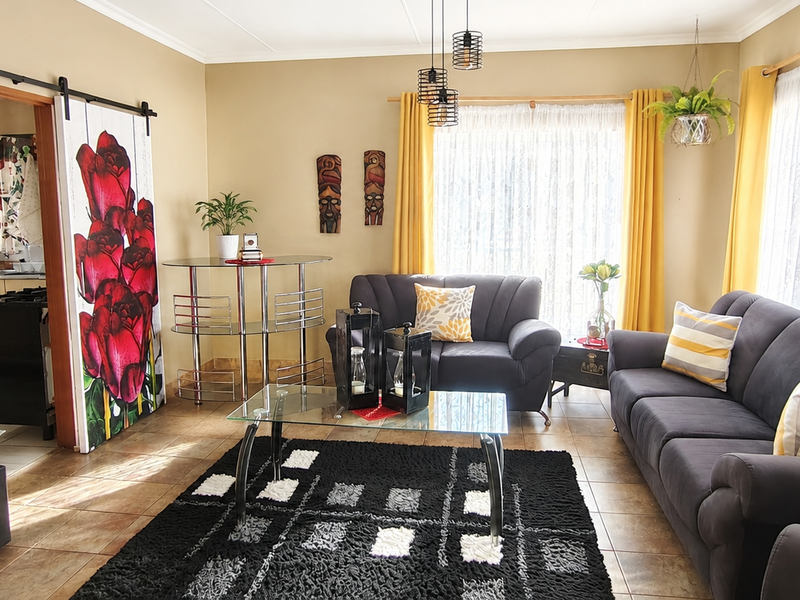 A comfortable living room featuring tiled flooring, a decorative sliding barn door, and direct access to the adjacent kitchen area.