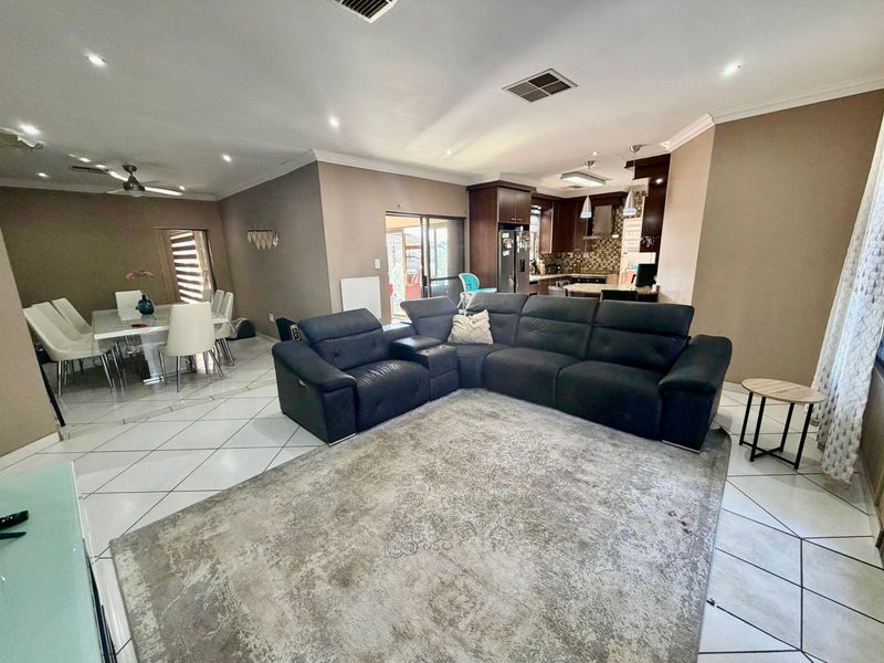 Spacious open-plan living and dining area featuring tiled floors, recessed lighting, and a modern kitchen with built-in cabinetry and an island.