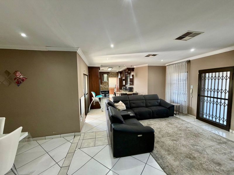Open plan living area featuring tiled floors, recessed lighting, and a connected kitchen with cabinetry and island, leading to a secure exterior entrance.