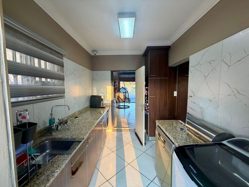 Functional scullery featuring granite countertops, ample built-in cabinetry, and tiled flooring, providing a practical workspace adjacent to the main living area.