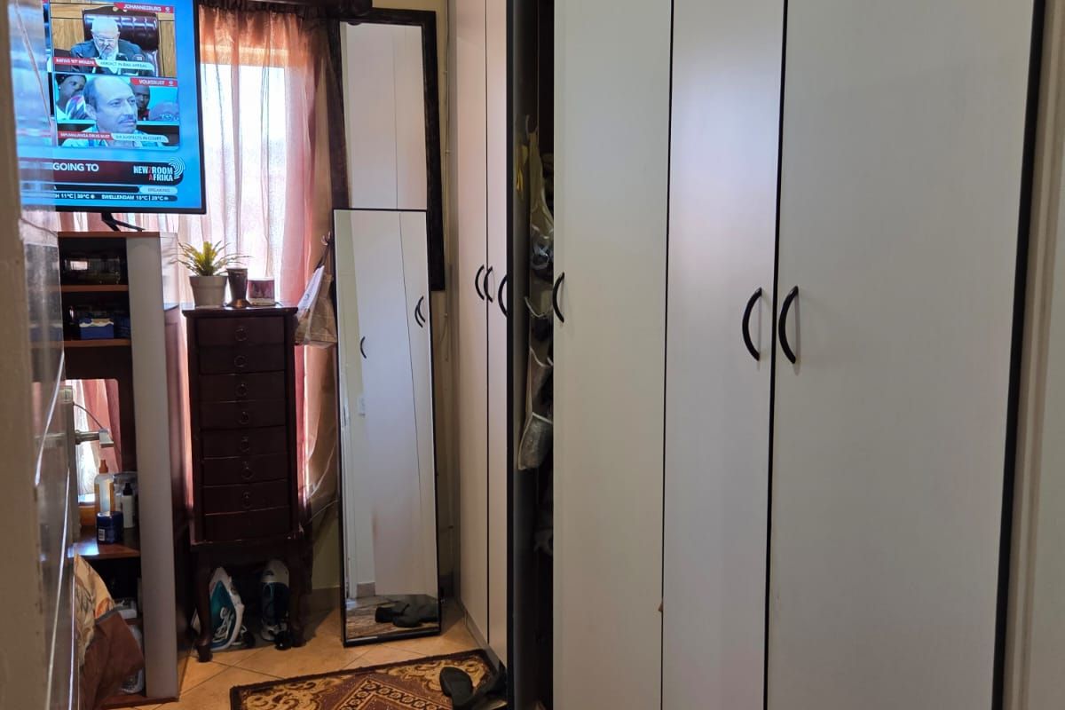 A bedroom featuring built-in cupboards with white doors and tiled flooring.