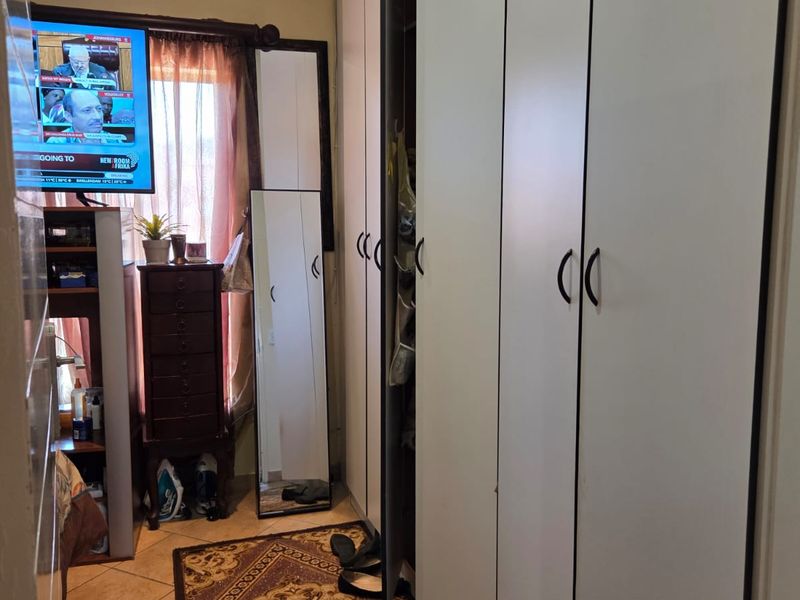 A bedroom featuring built-in cupboards with white doors and tiled flooring.