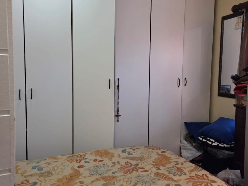 A bedroom featuring floor-to-ceiling built-in cupboards with white doors and recessed ceiling lighting.