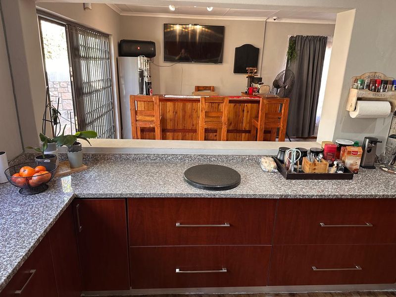 Open plan kitchen and bar area featuring granite countertops, dark wood cabinetry, and direct access to an outdoor patio through a security gate.