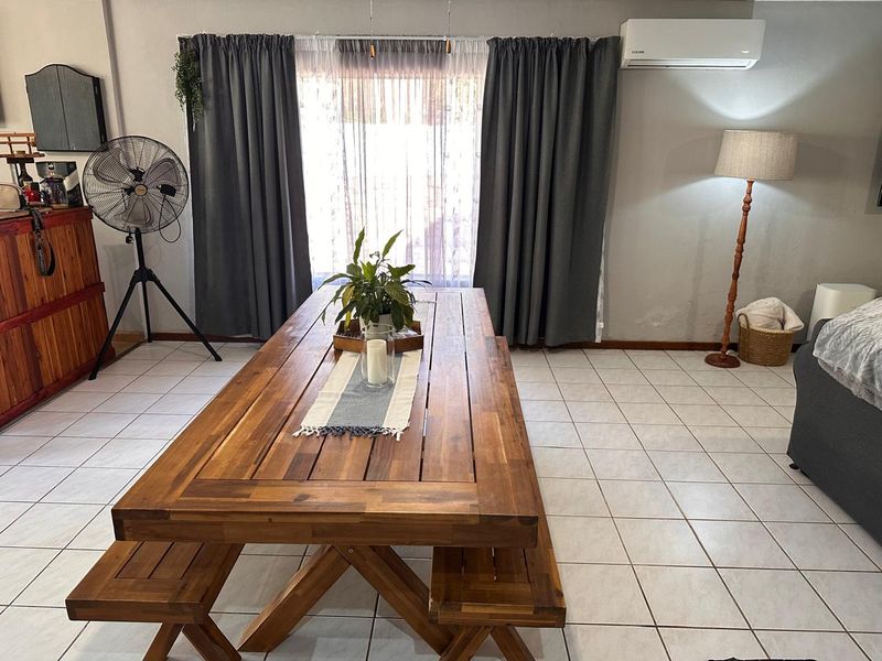 A dining area featuring tiled flooring and a wall-mounted air conditioning unit, with visible signs of wall moisture near the baseboard.
