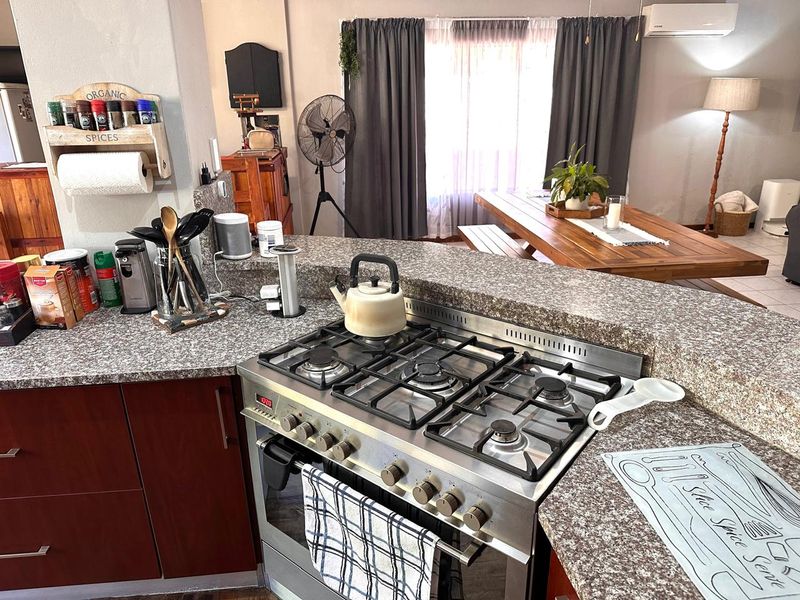 Open-plan kitchen and dining area featuring a gas stove, granite countertops, and built-in cabinetry, providing a functional space for cooking and dining.