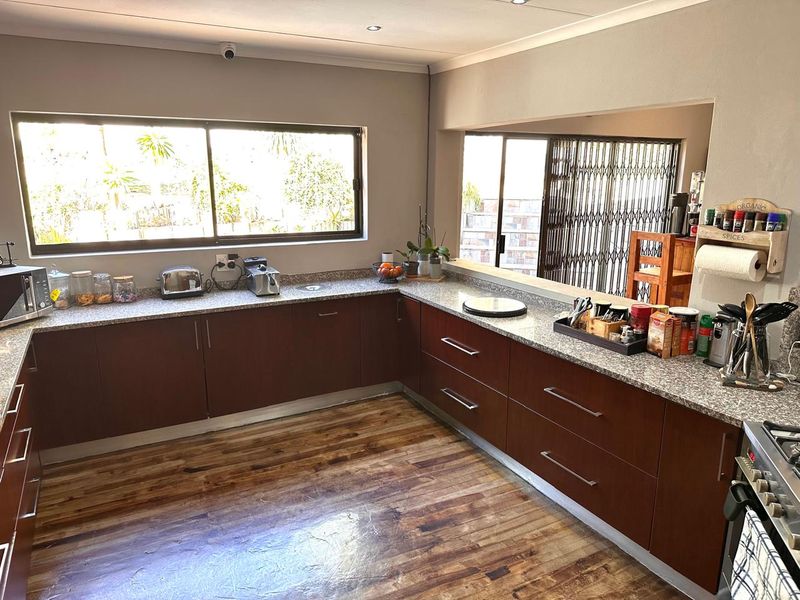 A functional kitchen featuring dark wood cabinetry, granite countertops, and laminate flooring, with a large window providing natural light and a view to the exterior.
