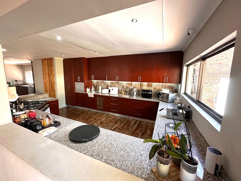 Spacious kitchen featuring dark wood cabinetry, granite countertops, a gas hob, and a tiled backsplash, offering ample workspace and storage.