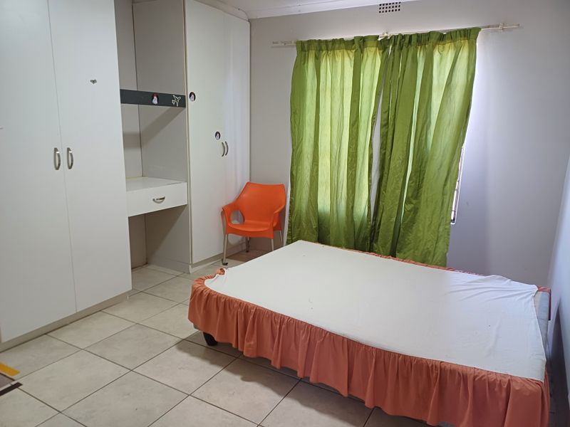 A functional bedroom featuring built-in cupboards with an integrated desk and tiled flooring.