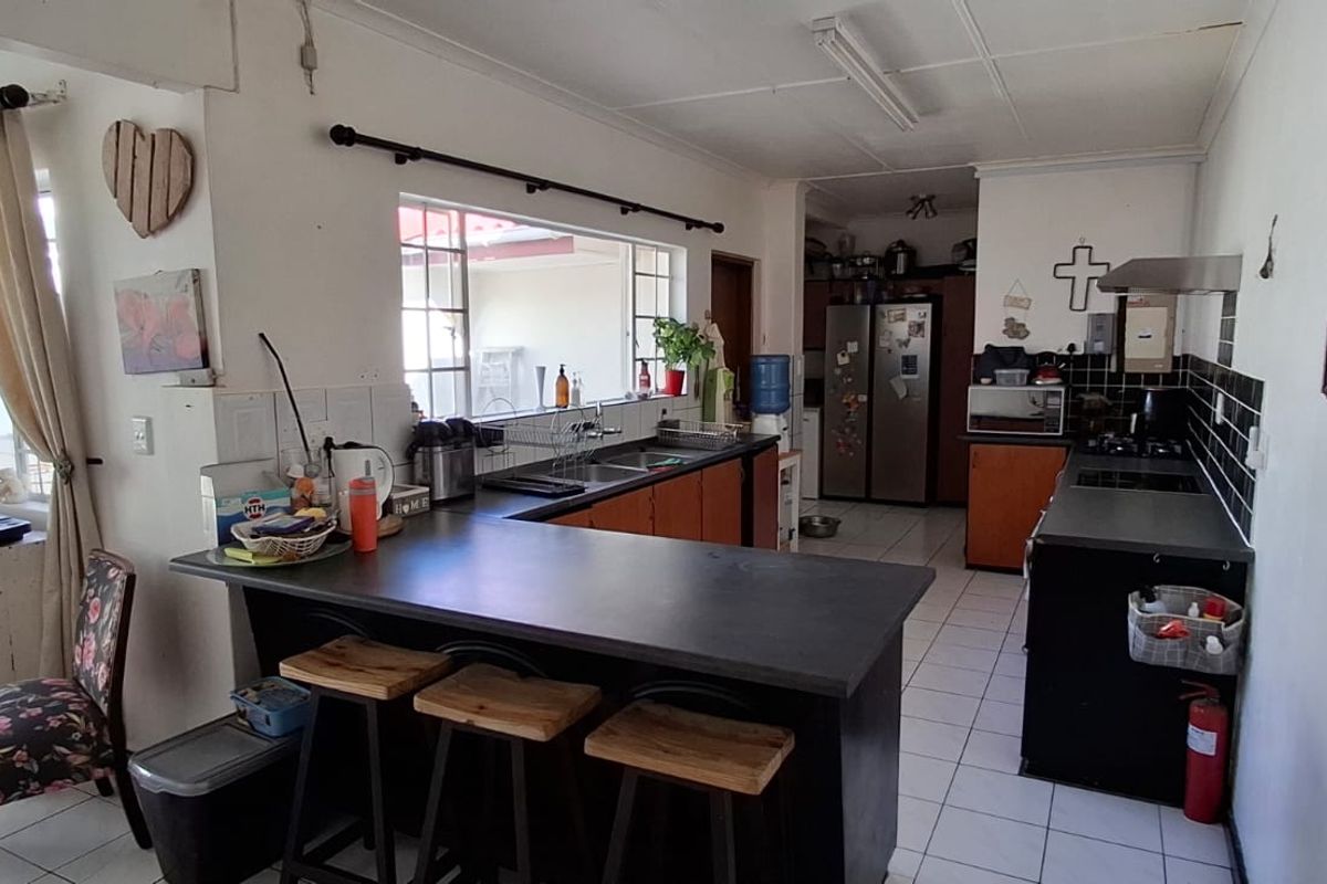 Functional kitchen featuring built-in cabinetry, laminate countertops, tiled flooring, and integrated cooking appliances with a breakfast bar area.