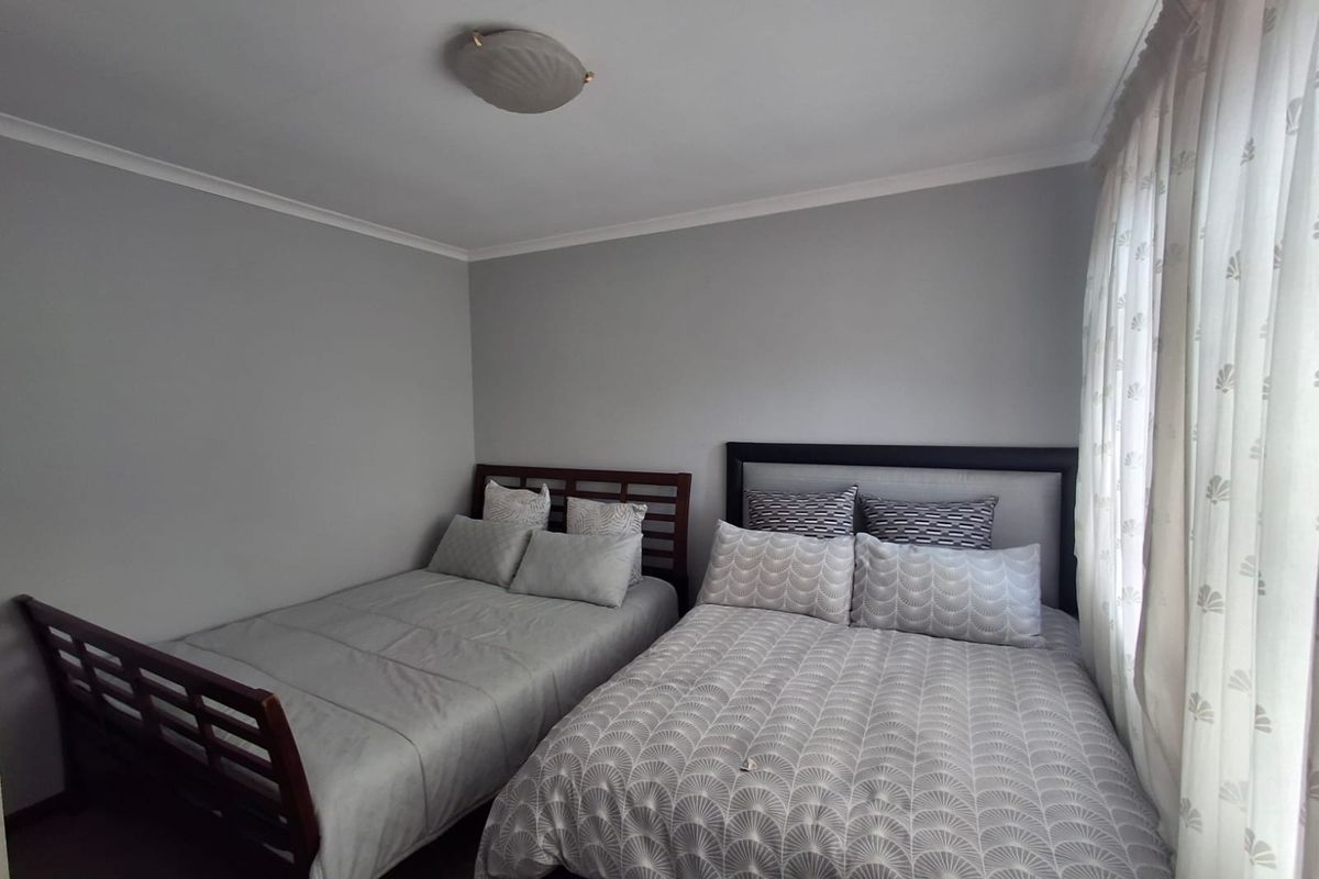 A functional bedroom featuring neutral wall tones, a ceiling light fixture, and window treatments.