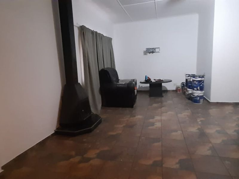 Living room featuring a freestanding fireplace and tiled flooring, requiring cosmetic updates to improve the overall aesthetic and finish.