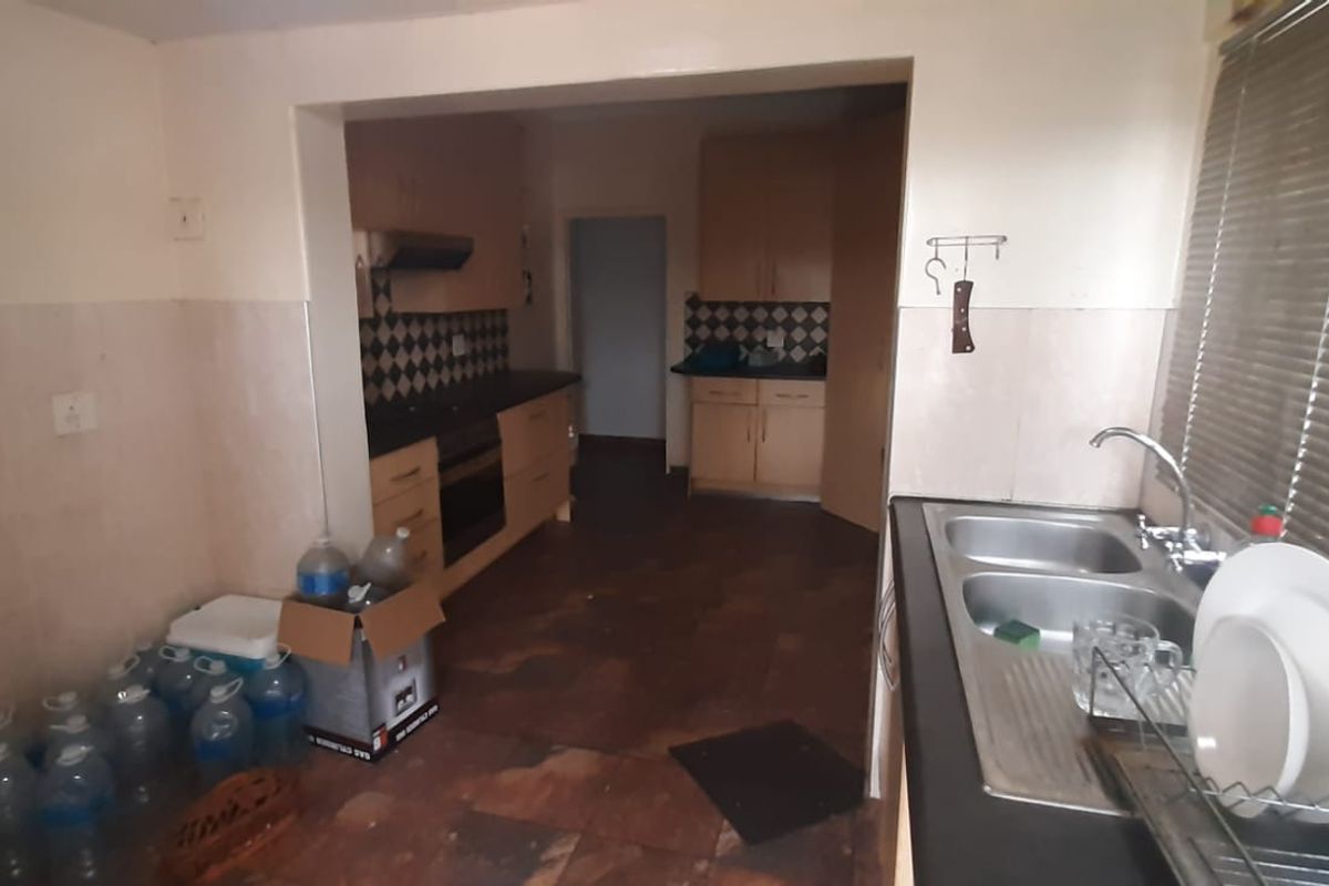 A functional kitchen featuring built-in cabinetry, a double bowl stainless steel sink, built-in oven, and extractor fan, with tiled flooring and splashbacks.